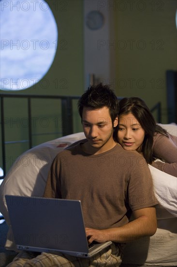 Asian couple looking at laptop