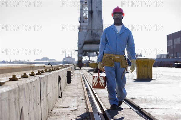 African American male construction worker carrying toolbox