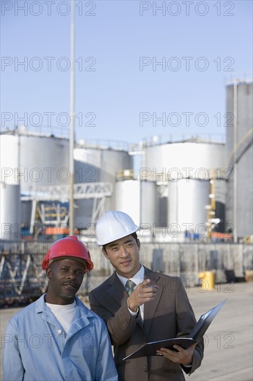 Multi-ethnic businessman and construction worker wearing hardhats