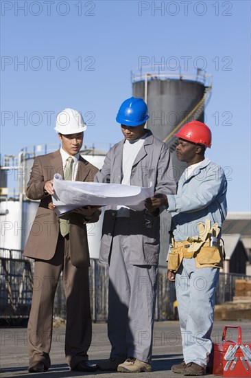 Multi-ethnic businessman and construction workers looking at blueprints