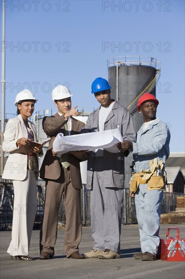 Multi-ethnic businesspeople and construction workers looking at blueprints