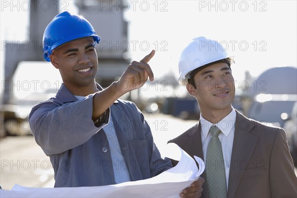 Multi-ethnic businessman and construction worker pointing