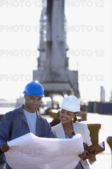 African American businesswoman and construction worker with blueprints