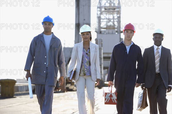 Multi-ethnic businesspeople and construction workers walking