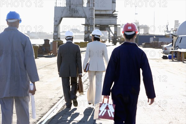 Multi-ethnic businesspeople and construction workers walking