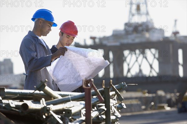 Multi-ethnic male construction workers looking at blueprints