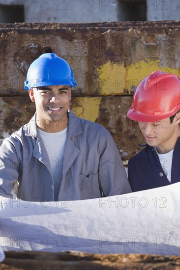 Multi-ethnic male construction workers holding blueprints