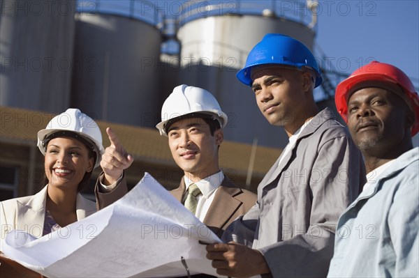 Multi-ethnic businesspeople and construction workers wearing hardhats