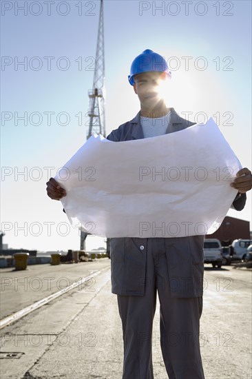 African American construction worker holding blueprints