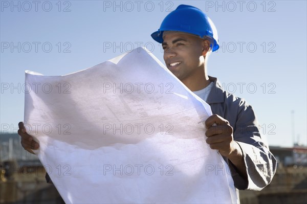 African American construction worker holding blueprints