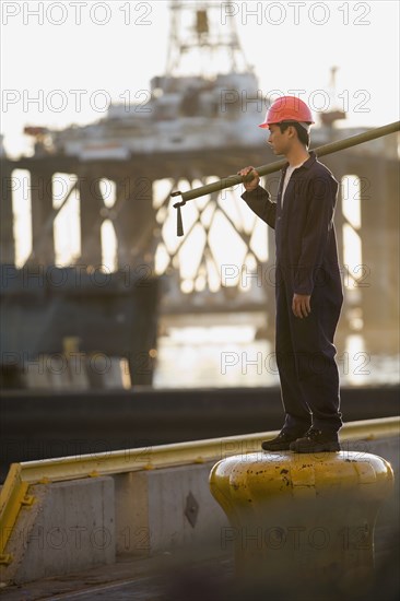 Asian male dock worker holding pipe