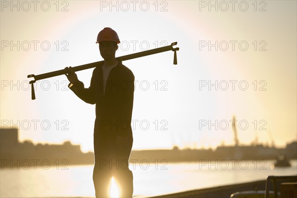 Asian male dock worker holding pipe