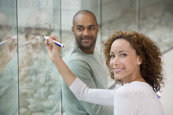 African businesswoman writing on clear dry erase board