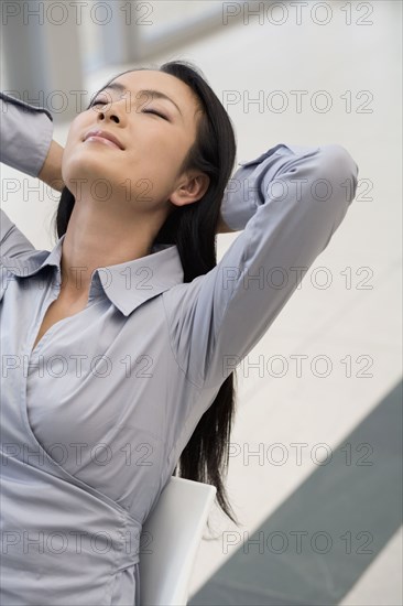 Asian businessman with hands behind head