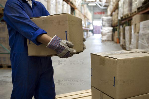 Worker carrying boxes in warehouse