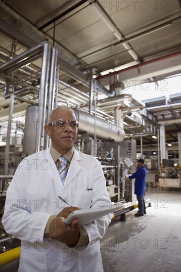 African scientist standing in factory with clipboard
