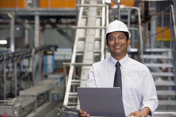 African manager with laptop in factory