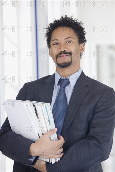 Confident African businessman holding paperwork