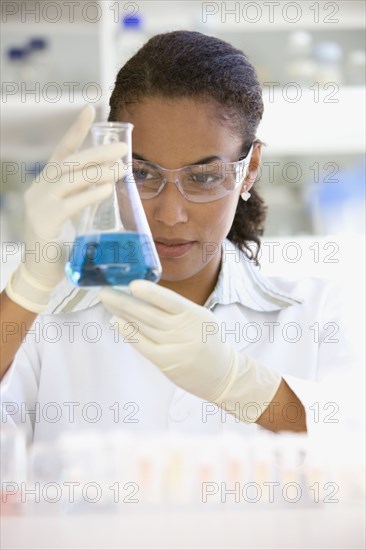 African scientist holding beaker of liquid in laboratory