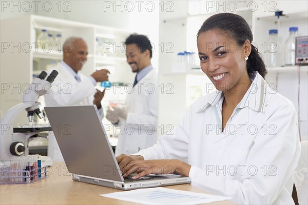 African scientist typing on laptop in laboratory