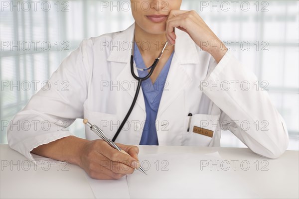 Mixed race doctor writing in hospital