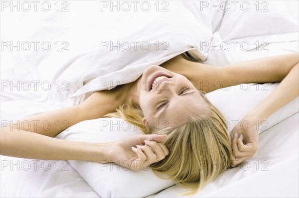 Smiling woman stretching in bed