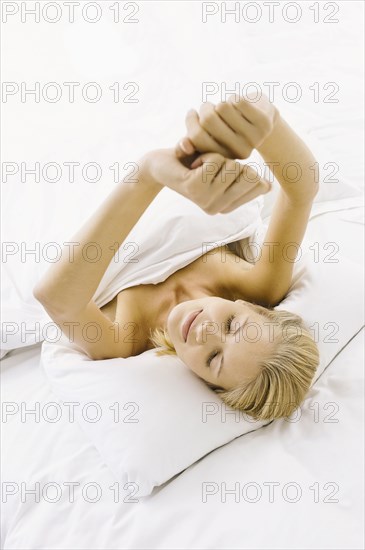 Smiling woman stretching in bed