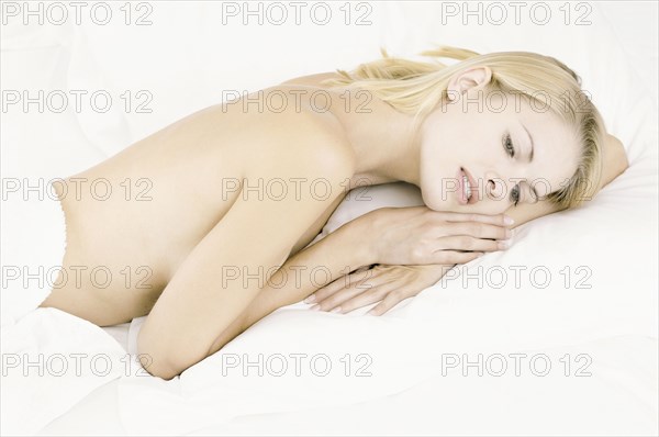 Nude woman laying in bed