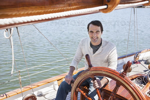 Caucasian man steering sailboat