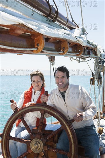 Caucasian couple steering sailboat