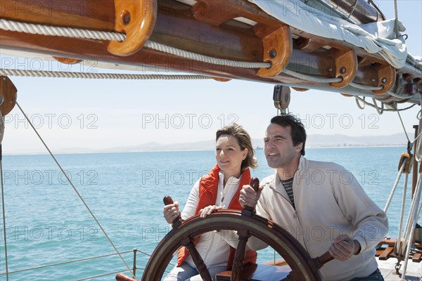 Caucasian couple steering sailboat