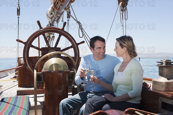 Caucasian couple toasting each other on sailboat