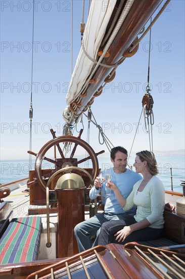 Caucasian couple toasting each other on sailboat