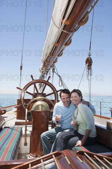 Caucasian couple toasting each other on sailboat