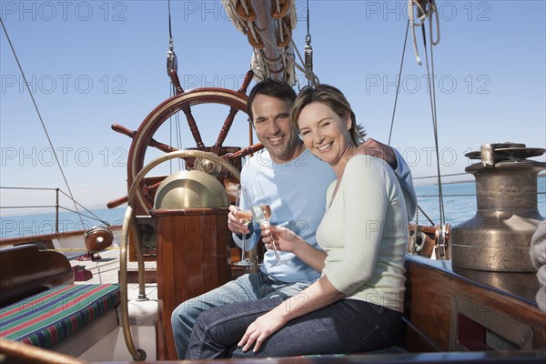 Caucasian couple toasting each other on sailboat