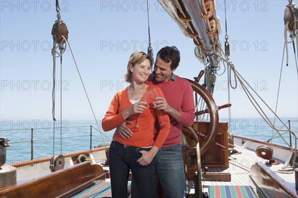 Caucasian couple toasting each other on sailboat