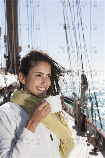 Caucasian woman drinking coffee on sailboat