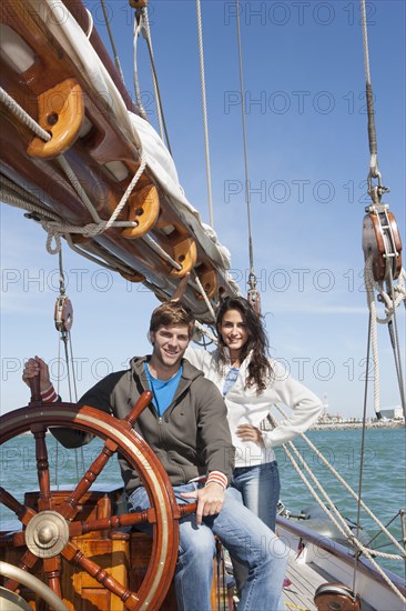 Caucasian couple at helm of sailboat