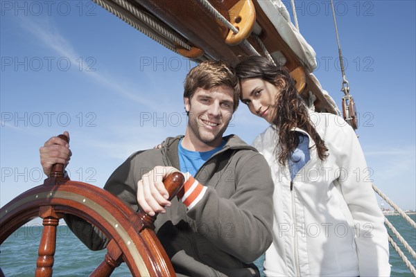 Caucasian couple at helm of sailboat