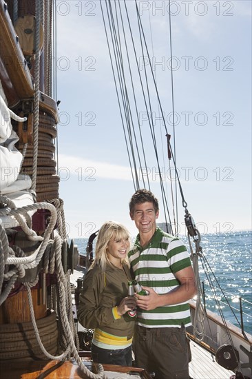 Caucasian couple drinking beer on sailboat
