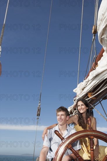 Caucasian couple at helm of sailboat