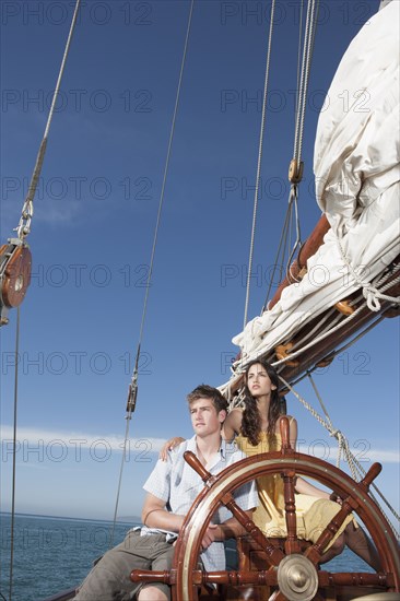 Caucasian couple at helm of sailboat