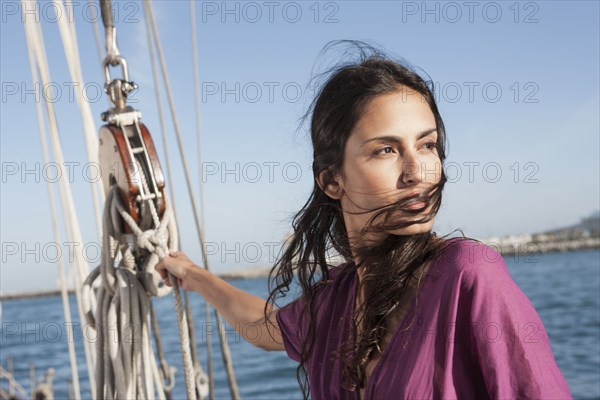 Caucasian woman hoisting sail on sailboat