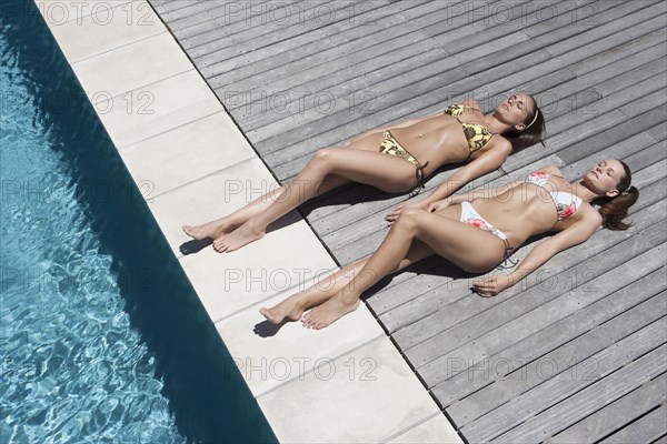 Caucasian women sunbathing by swimming pool