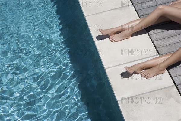 Caucasian women sunbathing by swimming pool