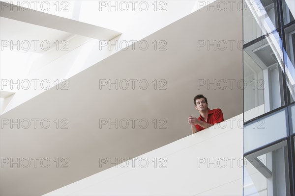 Caucasian man standing on atrium balcony