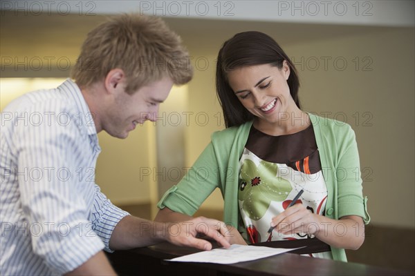 Caucasian woman talking to receptionist in hotel lobby