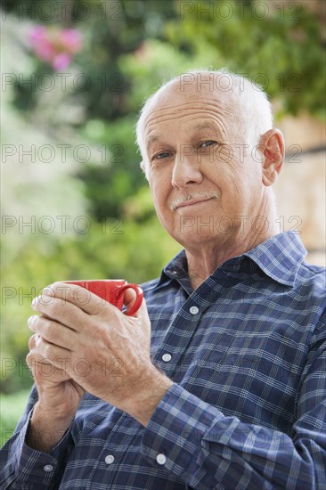 Senior Caucasian man having cup of coffee outdoors