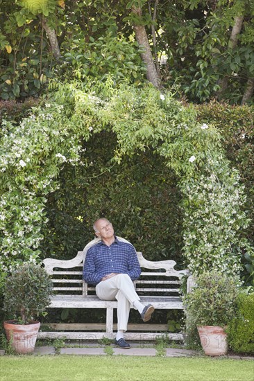Senior Caucasian man sitting on garden bench