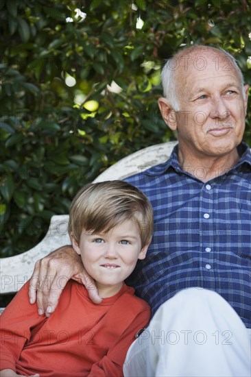 Caucasian boy sitting with grandfather on bench